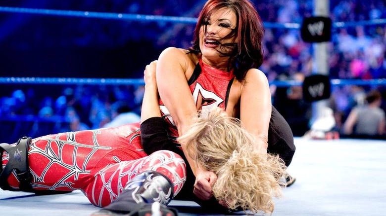 Victoria puts another woman in a headlock in the middle of the ring during a match in WWE.