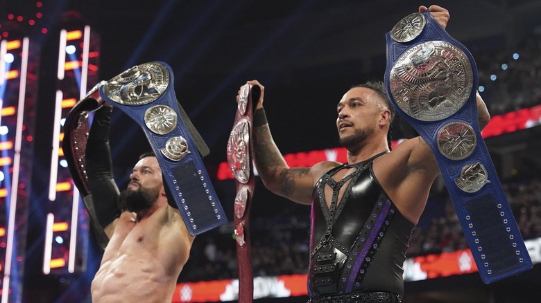 Finn Balor and Damian Priest hold their WWE tag team title belts aloft