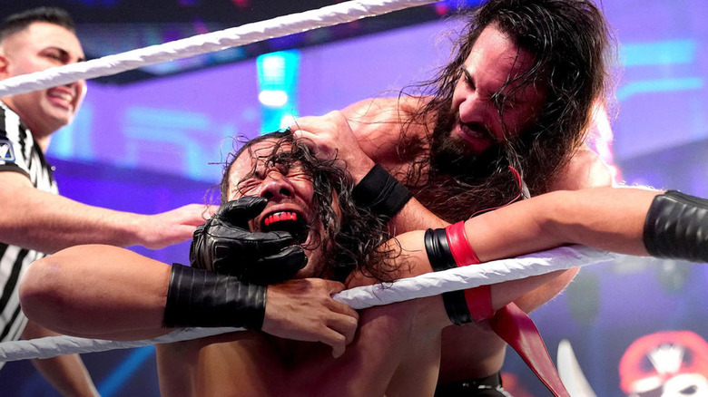 Seth Rollins grabbing Shinsuke Nakamura's face