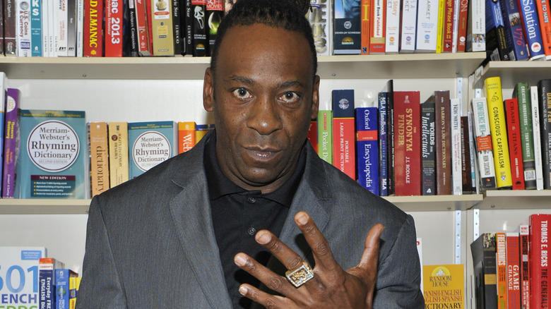 Booker T hold up WWE hall of Fame ring in front of book shelves