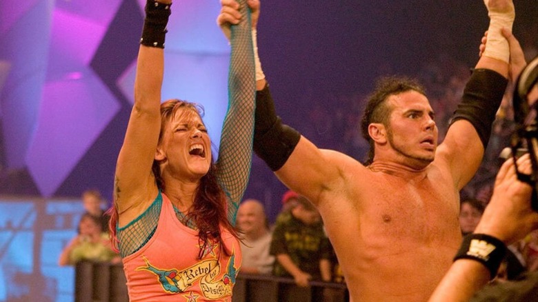 Lita has her hand raised by then-boyfriend Matt Hardy while standing outside of the ring following a win on 