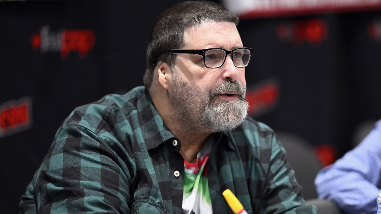 Mick Foley wearing glasses and green flannel shirt