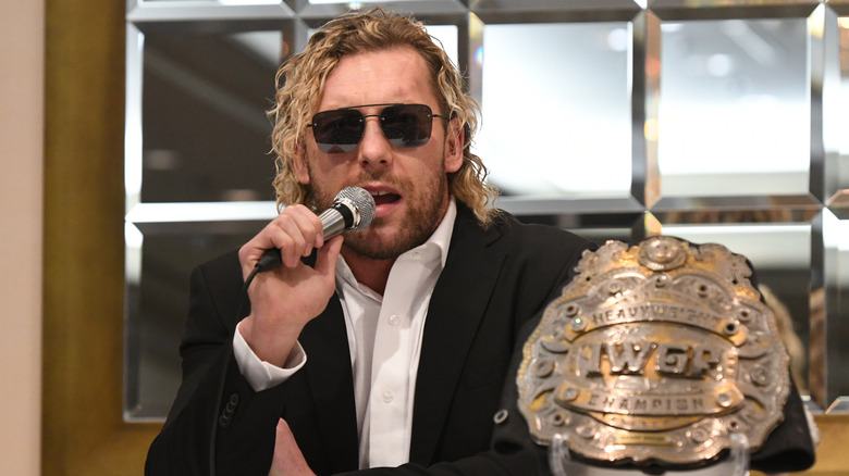 Kenny Omega (with IWGP Heavyweight Championship placed beside him) gives a speech during a NJPW press conference