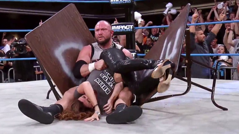 Bully Ray holding onto Dixie Carter through a broken table