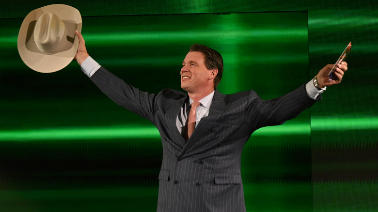 JBL posing to the crowd holding his cowboy hat and a card