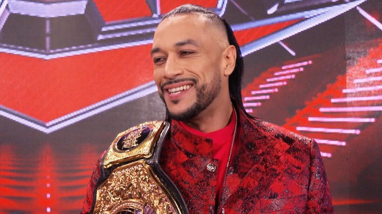 Damian Priest smiling with championship belt on shoulder