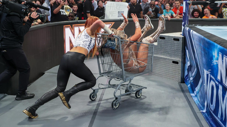 Becky Lynch pushes Tiffany Stratton in a shopping cart
