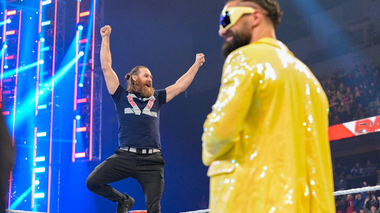 Sami Zayn raising his arms in front of Seth Rollins