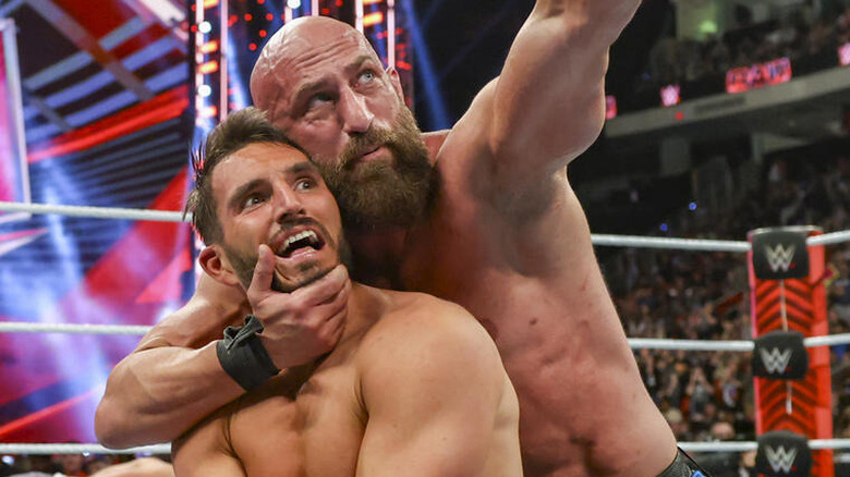 Tommaso Ciampa cradling Johnny Gargano's head while pointing