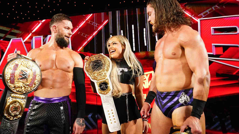 Finn Balor, Liv Morgan, and JD McDonagh holding title belts