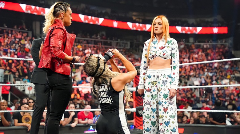 Trish Stratus kneeling before Becky Lynch