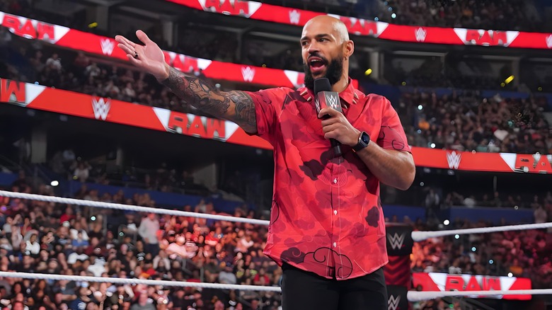 Ricochet with a microphone, holding out his hand