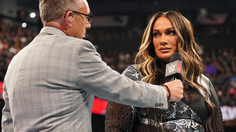Michael Cole holding out a microphone to Nia Jax