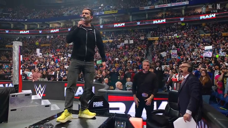 Punk speaking as he stands on top of the announce desk