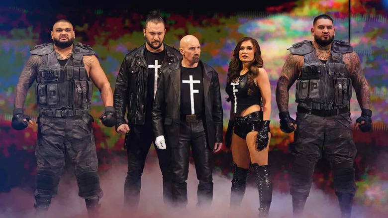 The Authors of Pain and Paul Ellering stand with Karrion Kross and Scarlett