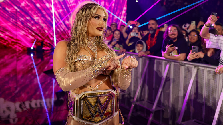 Tiffany Stratton taps her wrist on "WWE SmackDown" while walking down the ramp wearing her title