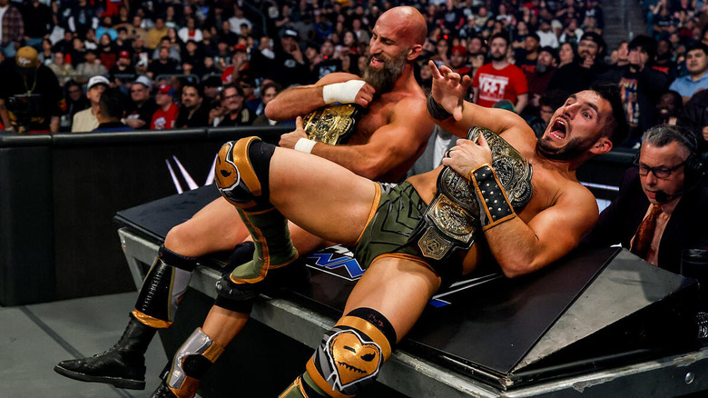 #DIY clutch their title belts while backing up over the announce table on "WWE SmackDown."