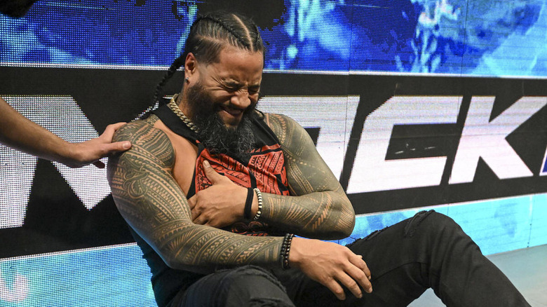 Jimmy Uso clutches his chest in pain beside the ring on "WWE SmackDown."