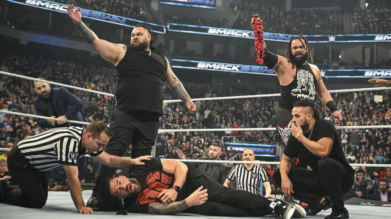 Bronson Reed celebrates with the New Bloodline as referees check on Roman Reigns on "WWE SmackDown."