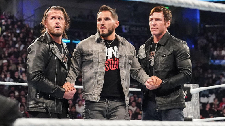 Motor City Machine Guns holding hands with Johnny Gargano in the ring on "WWE SmackDown."