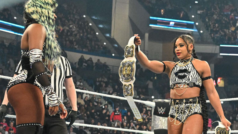 Bianca Belair handing a tag title belt to Naomi on "WWE SmackDown."