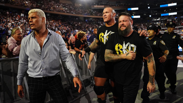 Police escort Cody Rhodes, Kevin Owens, and Randy Orton away from the ring