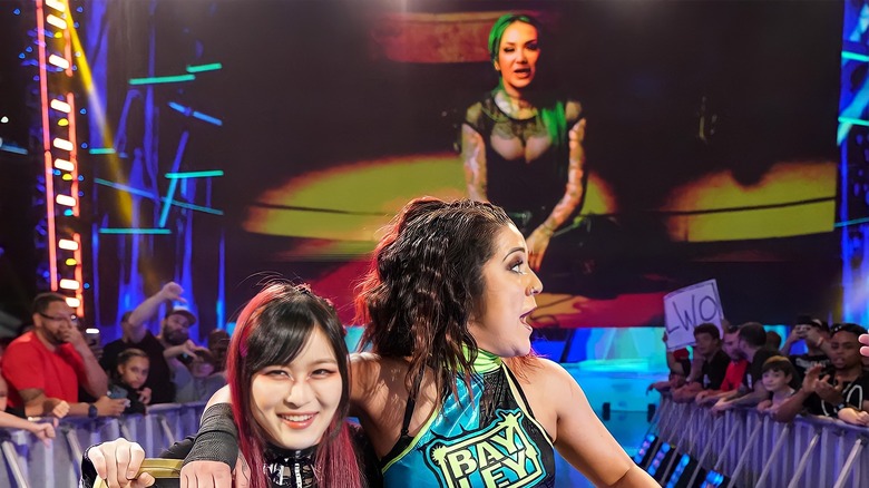 Shotzi appears on the screen behind Bayley and IYO SKY