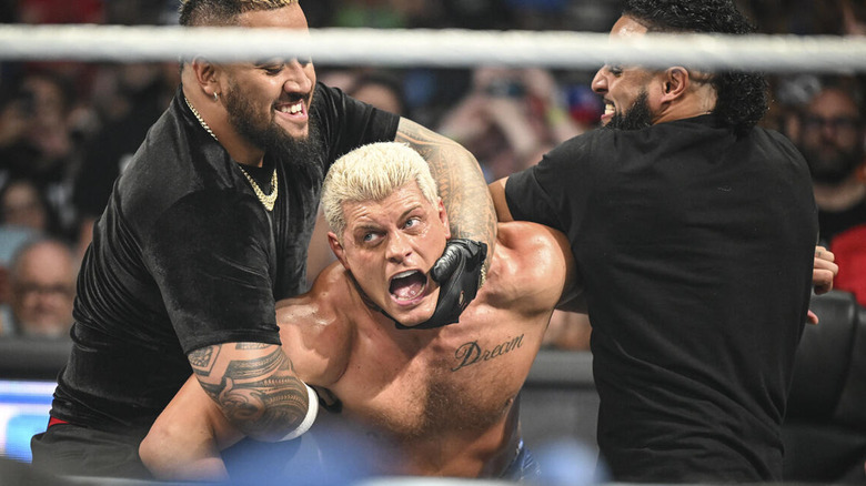 Cody Rhodes being restrained by Solo Sikoa and Tama Tonga