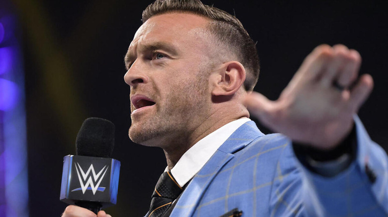 Nick Aldis holding microphone and gesturing