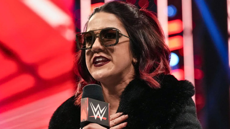 Bayley wearing sunglasses and talking into a microphone