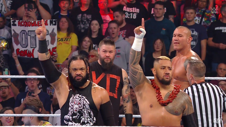 SIkoa and Fatu holding up the One symbol as Owens and Orton look on from behind