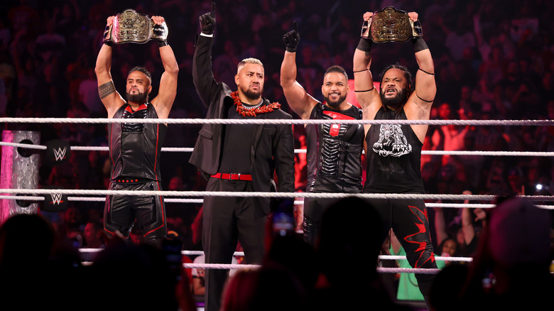 The Bloodline holding up the tag titles and celebrating