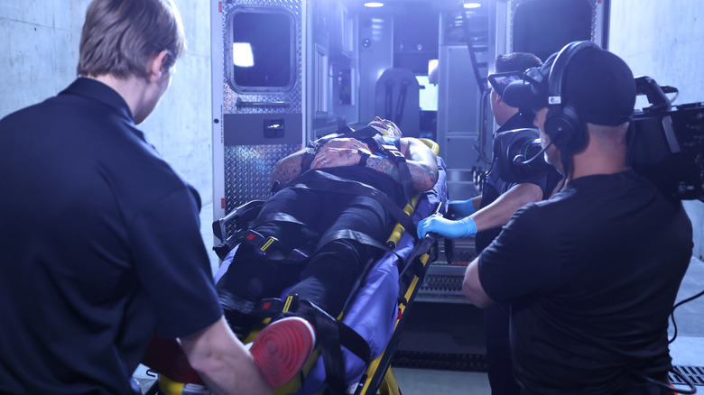 CM Punk is loaded into an ambulance as a camera man looks on