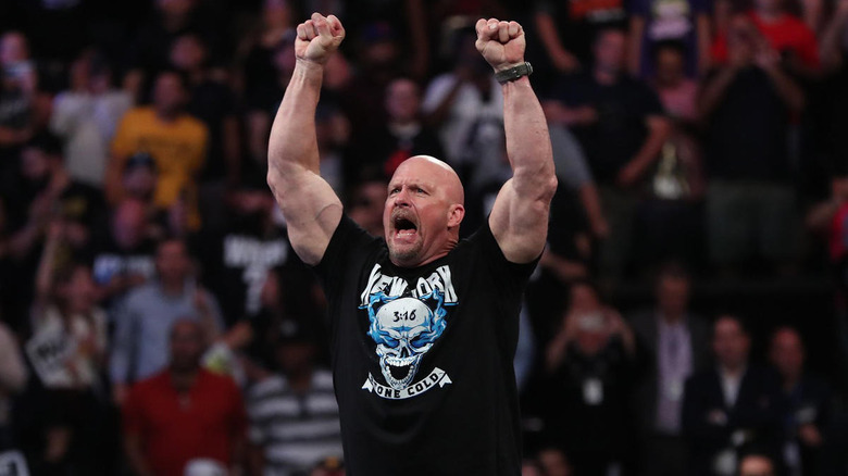 Steve Austin standing on ring post with arms raised