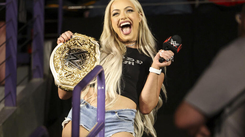 Liv Morgan laughing with title belt and microphone