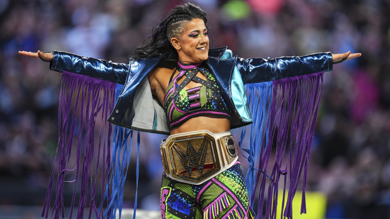 Bayley poses with one of WWE's many world titles