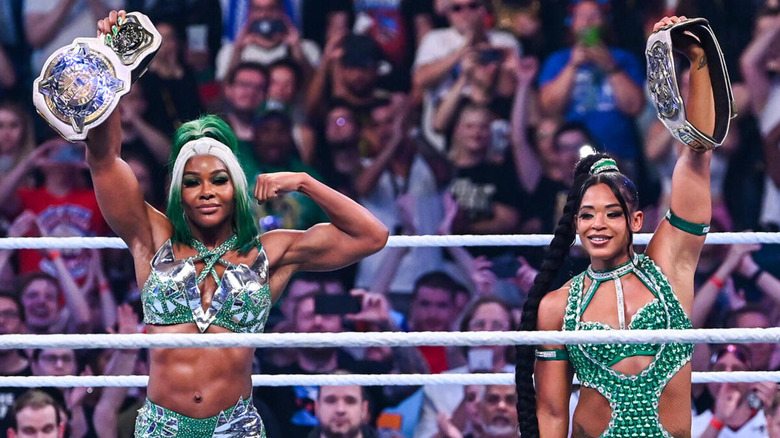 Jade Cargill and Bianca Belair raise their titles proudly.