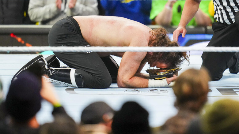 Sami Zayn on his knees cradling the Intercontinental title