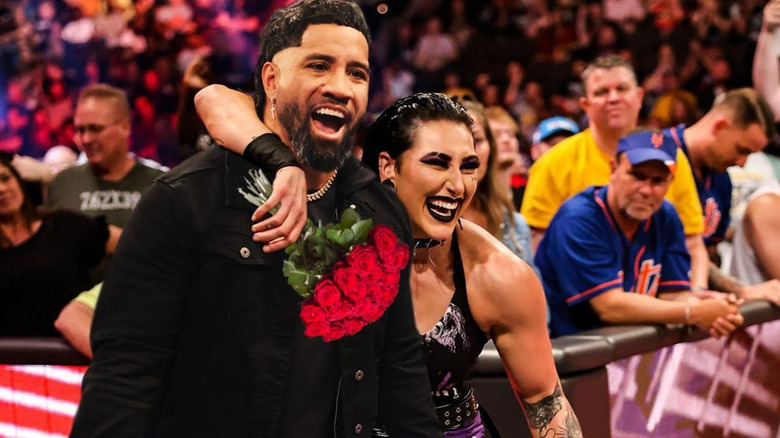 Rhea Ripley holding roses with arm around Jey Uso