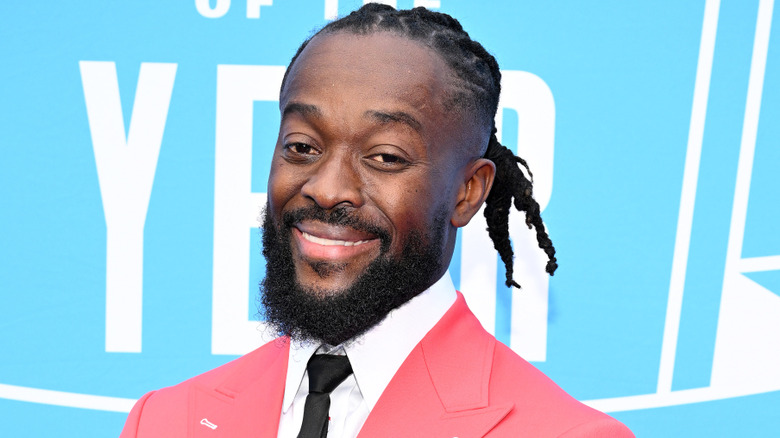 Kofi Kingston smiles towards a set of cameras at a red carpet event